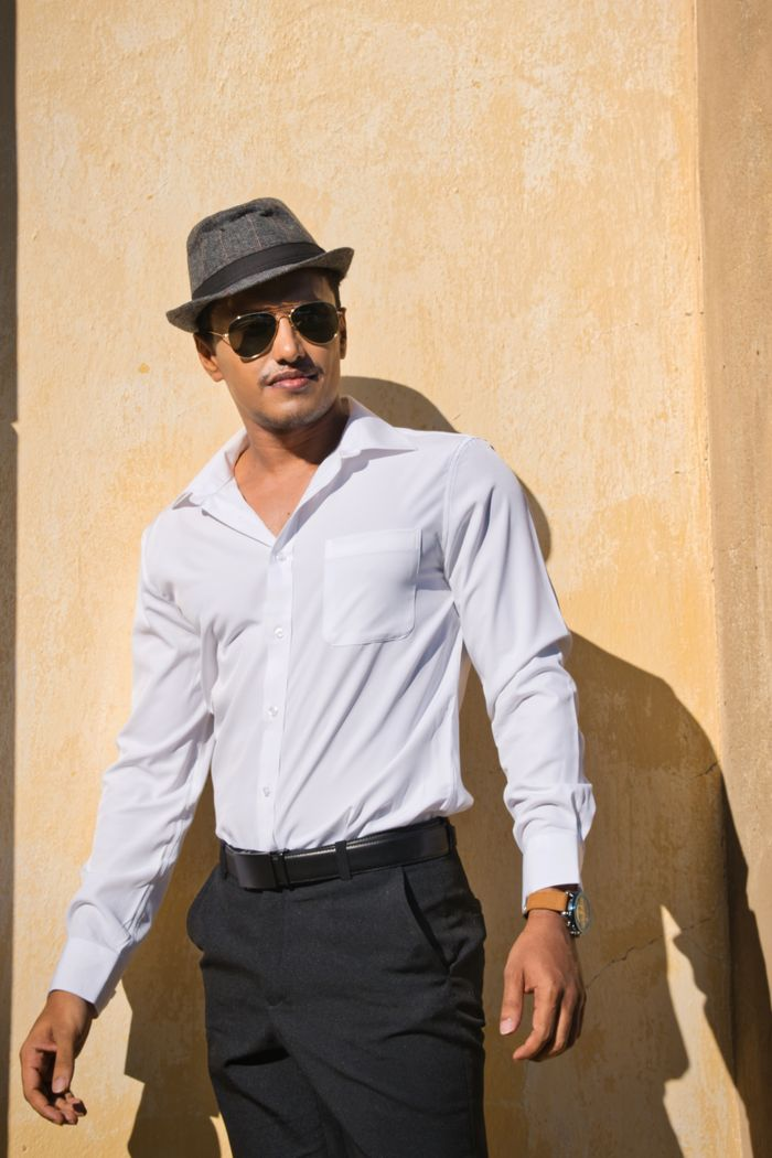 A confident male model poses outdoors in Sanssouci Park, Potsdam, wearing formal attire.